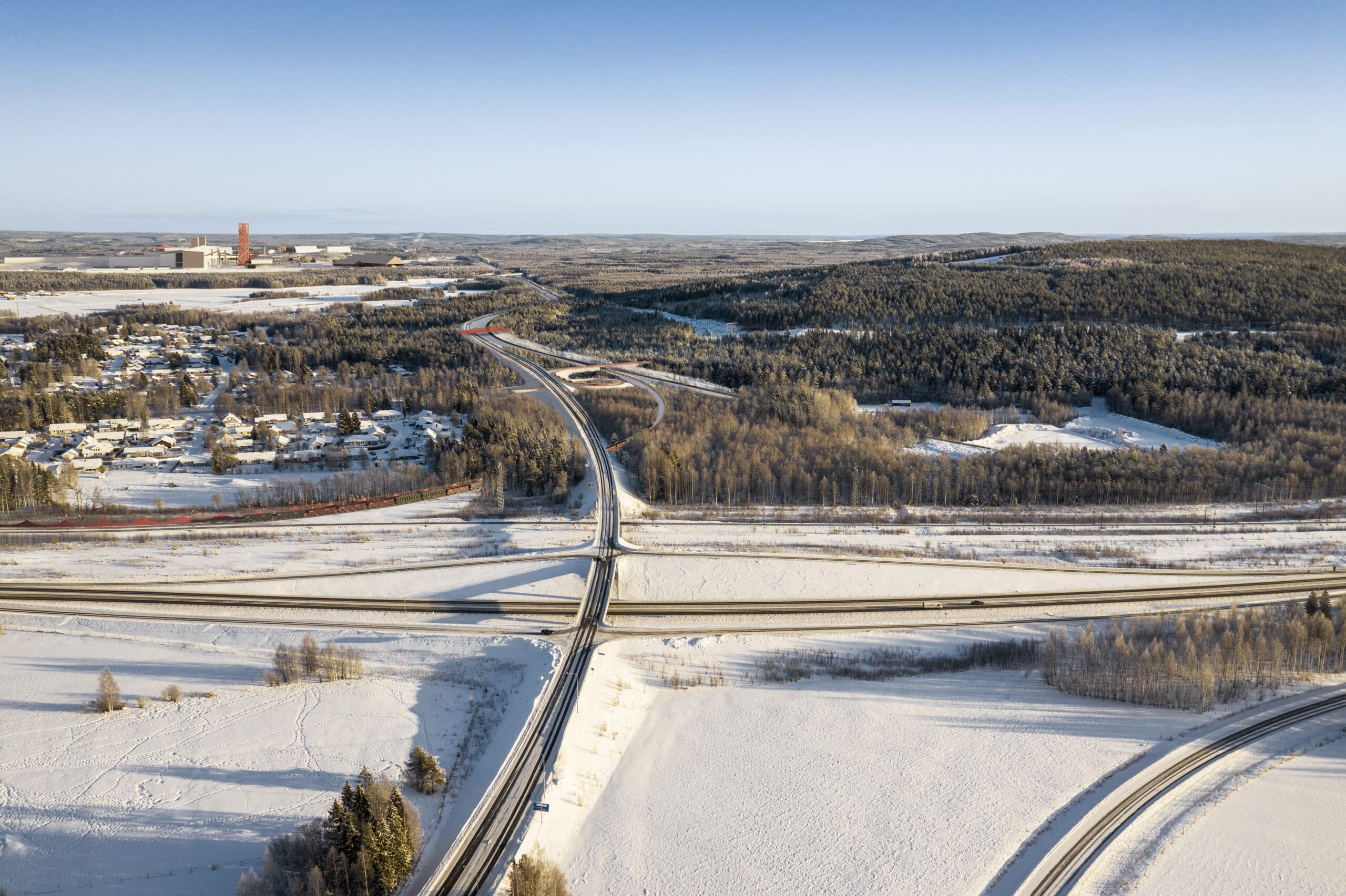 Visionsbild av hur järnvägen kan dras till Boden Industrial Park. På bilden syns skog, vägar, himmel och järnvägen med stålverket i bakgrunden.