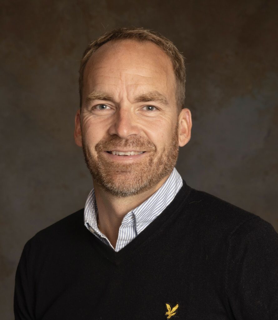 Portrait of Anders Eriksson, CEO of Markbygden Net, in a dark shirt with the company logo, smiling at the camera with a neutral background.