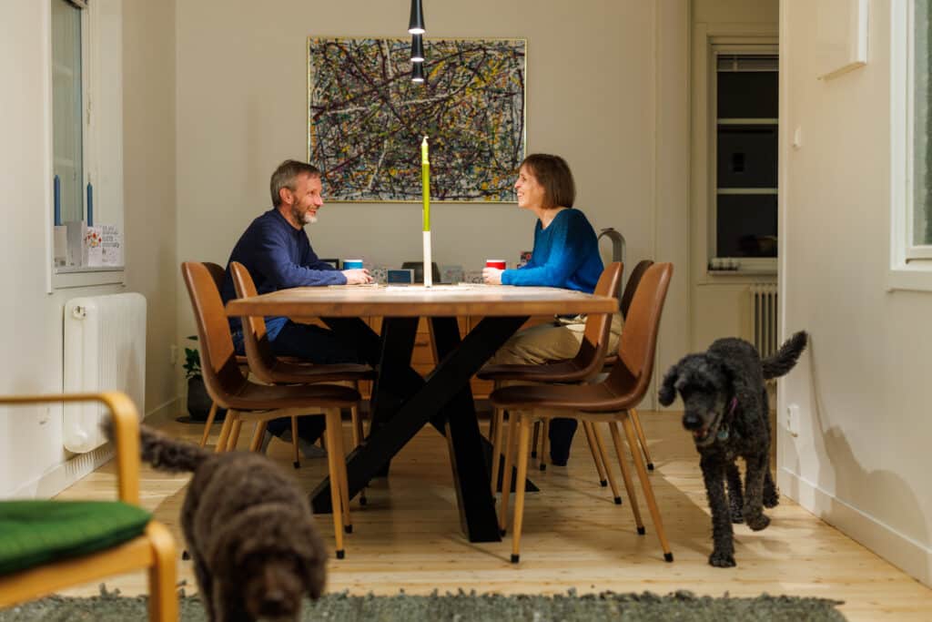 The Bramble couple at the kitchen table with the dogs next to them