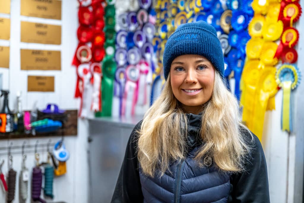 Nina in close-up in front of a wall of prize rosettes