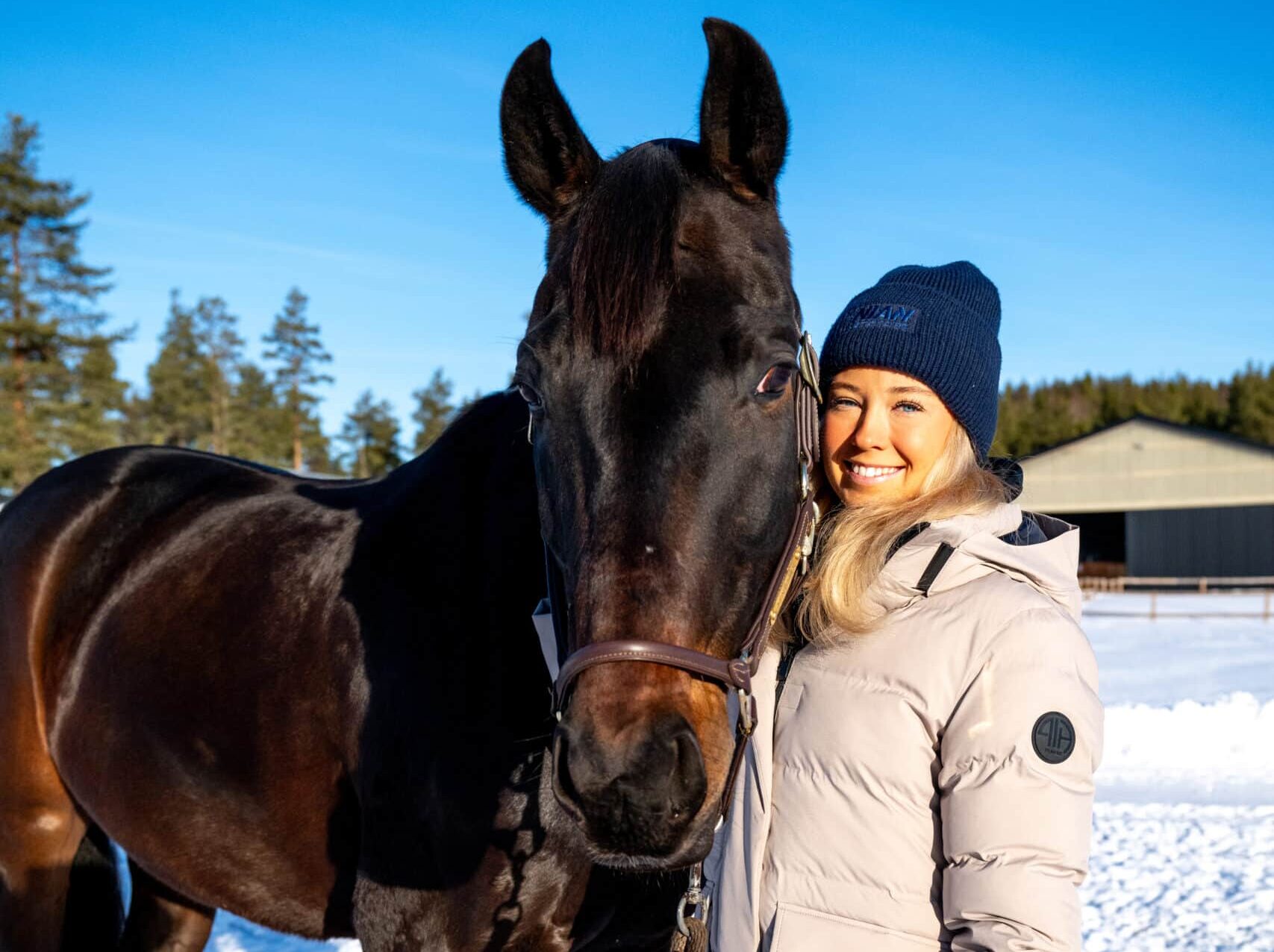 Nina Backman med häst utomhus i solig vintermiljö